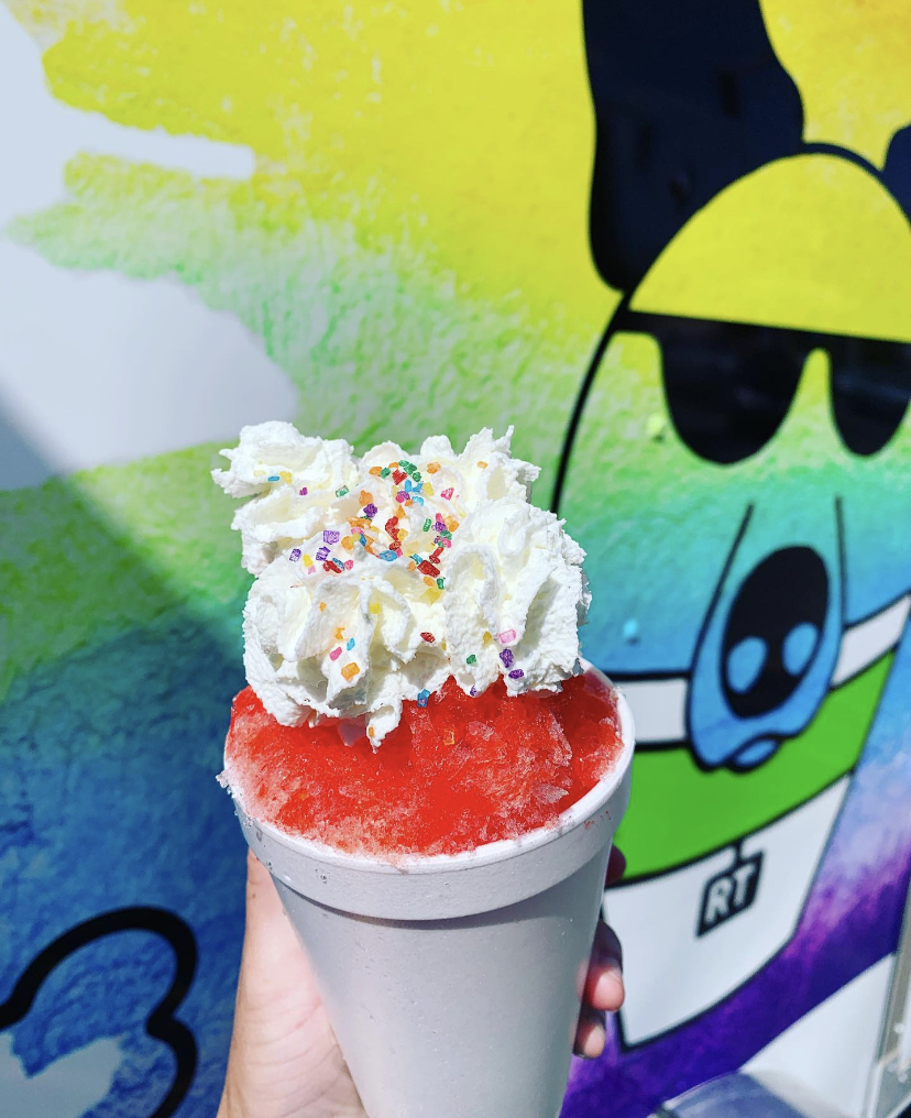Shave ice with whipped cream and a graphic of a dog in sunglasses behind it.